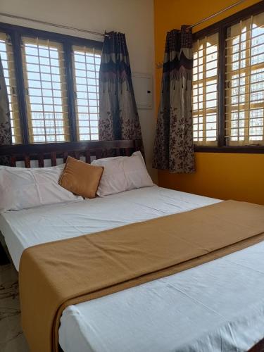 a bedroom with two beds with windows at Guru Residency Pondicherry in Puducherry