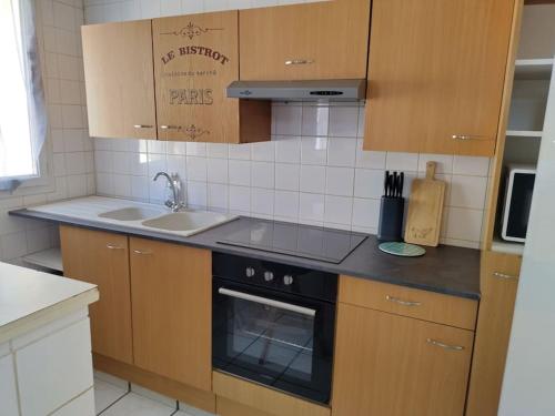 cocina con armarios de madera, fogones y fregadero en Spacieuse et confortable maison avec garage, en Anzin