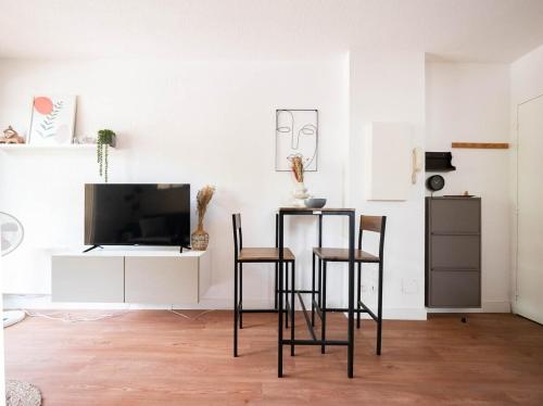 un salon avec deux chaises et une télévision dans l'établissement Le Richter - terrasse à Port Marianne, à Montpellier