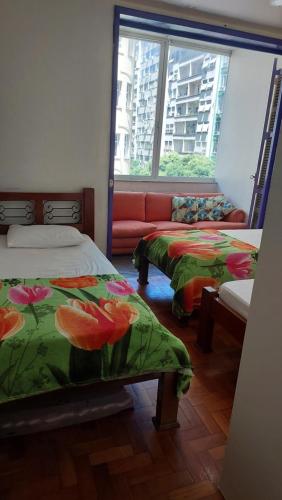 a room with two beds and a couch at Apartamento Copacabana vista lateral mar in Rio de Janeiro
