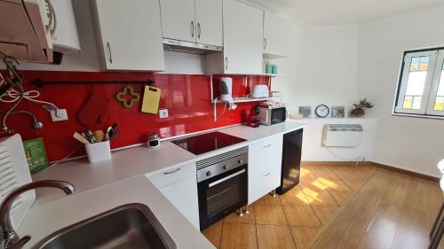 una cocina con armarios rojos y blancos y fregadero en Arcadas da Vila, en Manteigas