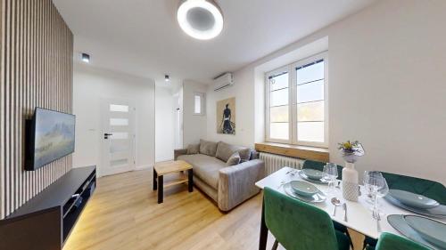 a living room with a couch and a table with green chairs at Ambient apartment in Žilina