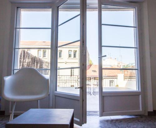 Cette chambre dispose d'une porte, d'une chaise et d'une fenêtre. dans l'établissement L'amoureux - terrasse et climatisation coeur de ville, à Montpellier