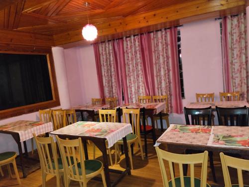 Balaji Continental في شيلونغ: غرفة طعام بها طاولات وكراسي وسقوف خشبية