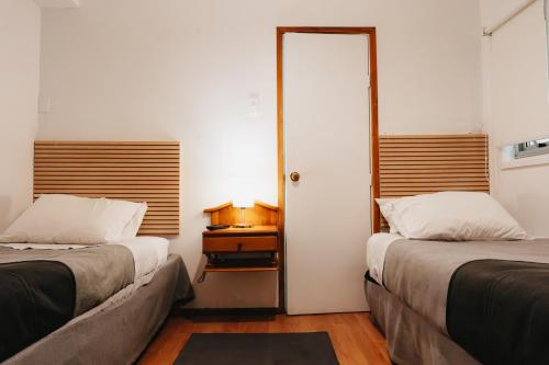a room with two beds and a door with a table at Hostal Concepcion in Concepción