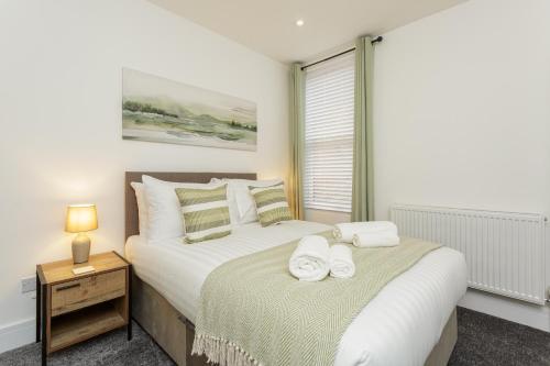 een slaapkamer met een bed met handdoeken erop bij Henderson Lodge - Cosy, modern 3 bed 2 bath house in Portsmouth