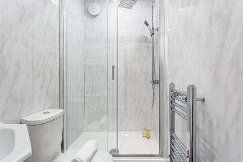 een witte badkamer met een douche en een toilet bij Henderson Lodge - Cosy, modern 3 bed 2 bath house in Portsmouth