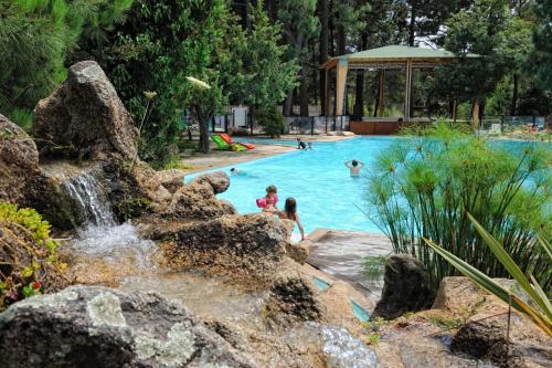 a pool with a waterfall and people in the water at Camping Mulinacciu in Lecci