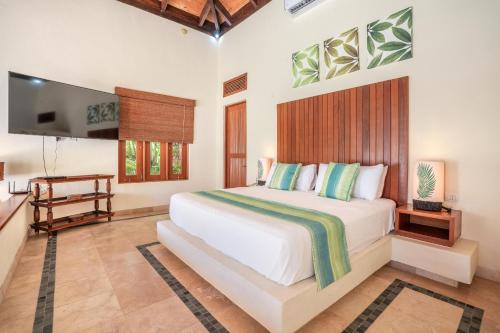 um quarto com uma cama branca e uma televisão em Newly added Tropical Bungalow at Green Village em Punta Cana