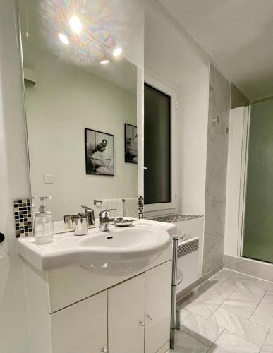 a white bathroom with a sink and a mirror at Les Remparts Antibes Location in Antibes