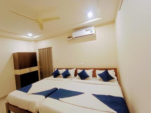 a bedroom with a bed with blue and white pillows at MGR RESIDENCY in Srikalahasti