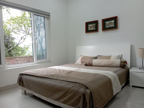a white bedroom with a large bed and a window at Pham Gia Riverside Retreat in Hà Nám