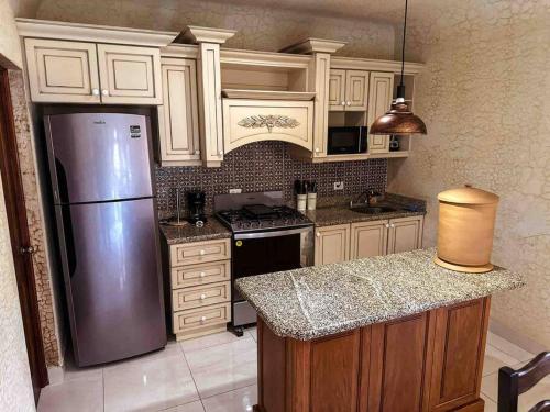 a kitchen with white cabinets and a stainless steel refrigerator at Villa Italiana, a 5min de Antigua in San Lorenzo El Cubo