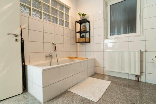 Urban Apartment - Stilvoll & im Herzen der Stadt في برمرهافن: حمام أبيض مع حوض استحمام ونافذة
