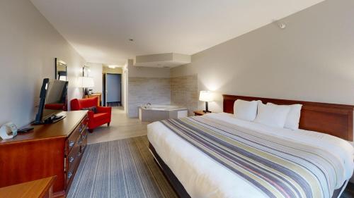 a hotel room with a large bed and a red chair at Country Inn & Suites by Radisson, Michigan City, IN in Michigan City