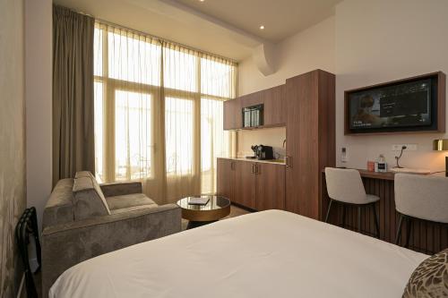 Habitación de hotel con cama, sofá y escritorio en Novallure Downtown - Short Stay Apartments, en La Haya