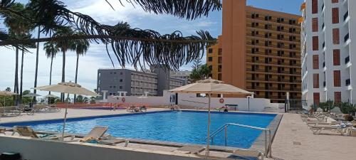 een zwembad met stoelen en parasols in een hotel bij 1 bedroom playa de la Americas in Playa Fañabe