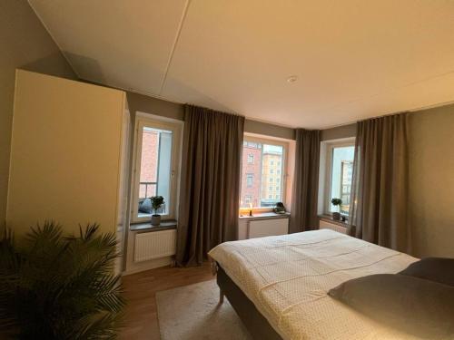 1 dormitorio con 1 cama, 2 ventanas y planta en New apartment in Hagastaden, en Estocolmo
