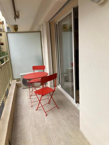 - deux chaises rouges et une table rouge sur un balcon dans l'établissement STUDIO à 50 mètres de la plage, à Antibes