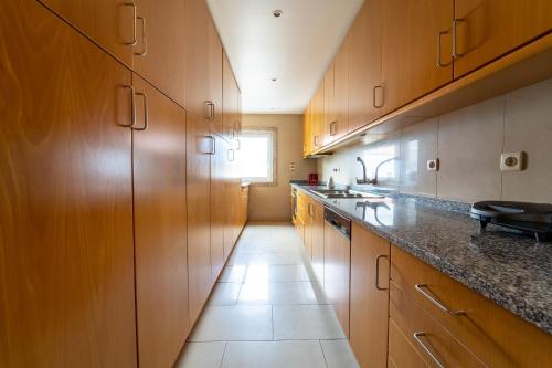 a kitchen with wooden cabinets and a long hallway at Taxa Duplex - T4 familiar no centro da cidade - Braga in Braga
