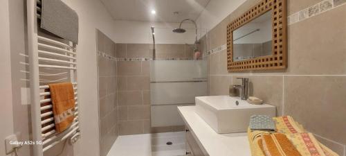 La salle de bains blanche est pourvue d'un lavabo et d'un miroir. dans l'établissement Gîte le Fort, à Vesseaux