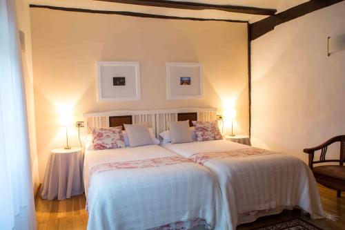 a bedroom with a large bed with two lamps at Casa de la Cadena in Asiáin