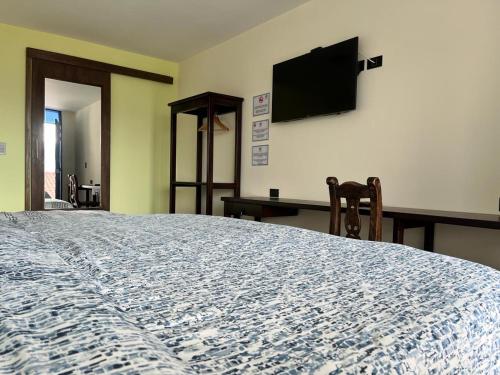 a bedroom with a large bed with a television on the wall at Hotel Cabañas San Cayetano in Paipa