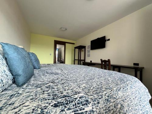 a bedroom with a bed with blue pillows and a television at Hotel Cabañas San Cayetano in Paipa