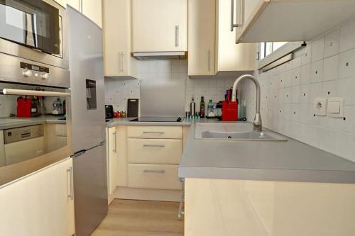 une cuisine avec des armoires blanches et un évier dans l'établissement Esterel Plage I Bord de mer Fréjus I Clim I 4 personnes, à Fréjus