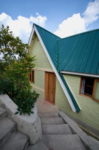 a green house with a green roof and some stairs at Hyena Hill Lodge in Sanga