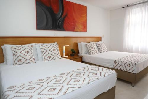 um quarto com duas camas e um quadro na parede em Hotel Guane em Bucaramanga