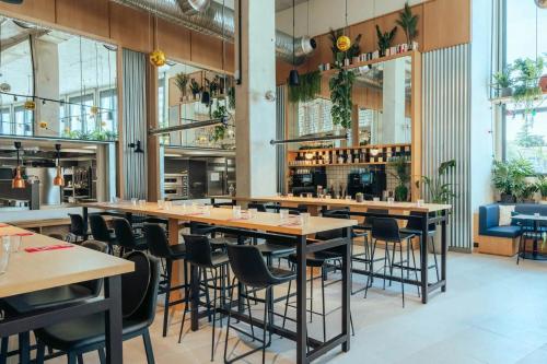 un ristorante con tavoli e sedie in legno e piante di JOST Hôtel Lille Centre a Lille