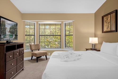a bedroom with a bed and a television and a chair at Sunny Summer Awaits - Renovated Townhome by Disney! in Orlando