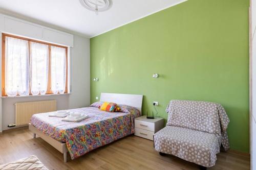 een groene slaapkamer met een bed en een stoel bij Casa Ristrutturata Parking Condominiale in Diano Marina