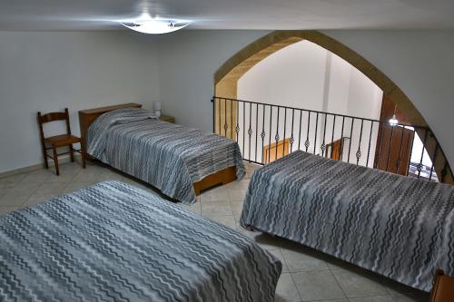 a room with two beds and a chair and a balcony at Holiday Home Castle Salemi - Casa Vacanze in Salemi