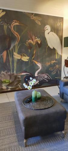 a living room with a table with a bird painting at Landhaus am Sonnenberg in Bad Bertrich