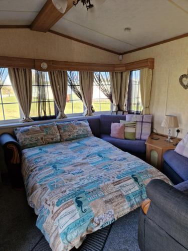 a bedroom with a blue bed and a couch at Static Caravan KL13 in Bettws-Evan