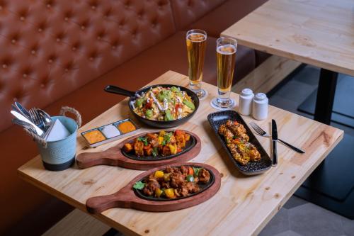 a table with three dishes of food and two glasses of beer at Hilton Garden inn Dubai Jumeirah in Dubai