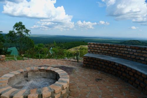 a brick fire pit with a view of the countryside at Hyena Hill Lodge in Sanga