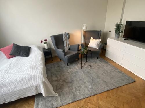 a bedroom with a bed and two chairs and a television at Cozy Ostermalm Studio in Stockholm