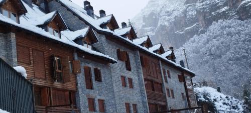 un edificio cubierto de nieve con una montaña en el fondo en Duplex Calle El Tillo, en Escarrilla