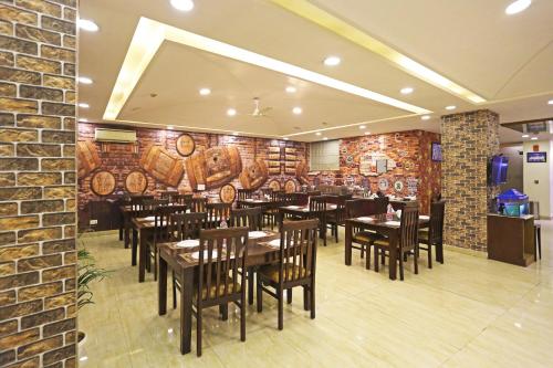 ein Restaurant mit Holztischen und -stühlen und Ziegelwand in der Unterkunft Hotel D'Capitol - Delhi Airport in Neu-Delhi