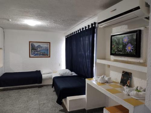 Habitación de hotel con 2 camas y TV en Íkaro Suites Cancún, en Cancún