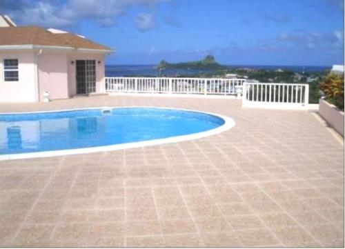 una piscina frente a una casa con el océano en Marina View Villa en Gros Islet