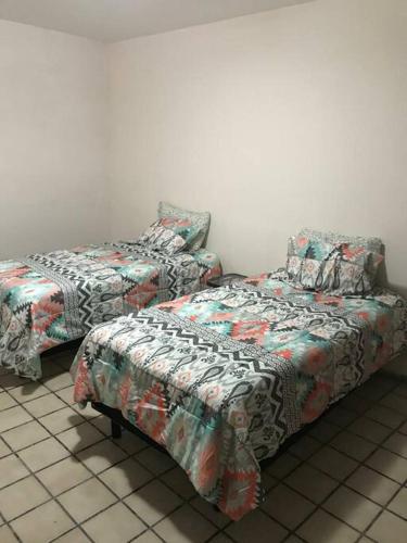 two beds and a chair in a room at Excelente casa a unos pasos del blvd M. Alemán in Gómez Palacio
