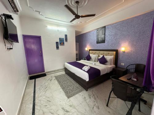 - une chambre avec un lit aux murs violets et une table dans l'établissement Live Free Hostel Rishikesh, à Rishikesh