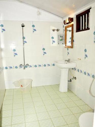a white bathroom with a sink and a toilet at Angeo Beach House in Alleppey