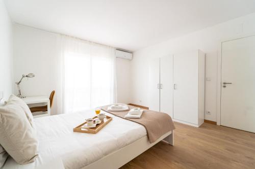 a white bedroom with a bed with a tray on it at Feliciano Ramos 3 - T4 familiar perto do centro da cidade - Braga in Braga