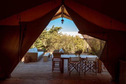 卡帕爾比奧的住宿－Glamping Terre di Sacra in Tuscany，木制甲板上的帐篷,配有桌椅