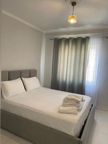 een slaapkamer met een bed met witte lakens en een raam bij Fishta hotels in Velipojë